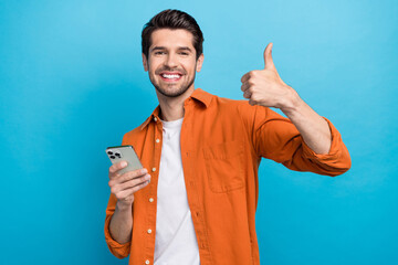 Aufkleber - Portrait of handsome cheerful guy hold iphone apple gadget toothy smile demonstrate thumb up isolated on blue color background