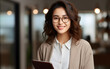 © Jumpee to do - Portrait of an attractive young Asian woman, a company worker in glasses, smiling and holding a digital tablet, standing in an office background