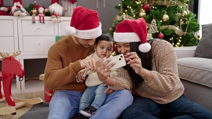 Sticker - Couple and son using smartphone sitting on floor by christmas tree at home