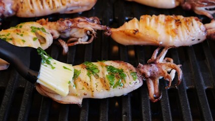 Sticker - cooking squids on grill, brush with olive oil and spices. Slow Motion. Close up