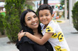 © Daniel - Portrait of a latina mother hugging her son smiling and looking at the camera.