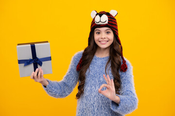 Poster - New Year or Christmas holiday gift. Happy teenager, positive and smiling emotions of teen girl. Child with gift present box on isolated studio background. Gifting for kids birthday.