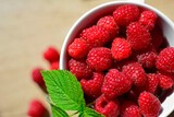 świeże maliny w kubku na stole, czerwone maliny, aromatyczne, soczyste maliny z zielonym listkiem, fresh raspberries in a cup, red raspberries, juicy raspberries with a green leaf, Rubus idaeus