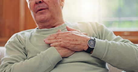 Hands, heart attack or condition with a senior man in pain closeup in the living room of his retirement home. Healthcare, chest or cardiac arrest with an elderly person breathing for lung oxygen