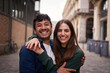 Portrait of young multiracial couple embracing happy smiling face on street. Friends cheerful hugging people positive expression looking at camera. Nice loving partner posing for photo outdoor.