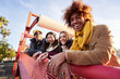 © CarlosBarquero - Multi-ethnic group smiling friends gathered on street leaning on railing. Happy young people enjoying together outdoors pose for portrait. Social relationships in college students of Generation z.