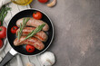 Frying pan with tasty homemade sausages, rosemary and tomatoes on brown textured table, flat lay. Space for text