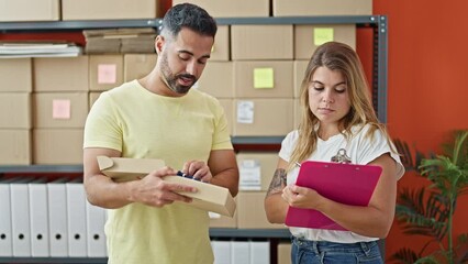 Wall Mural - Man and woman ecommerce business workers packing clothes on cardboard box writing on document at office