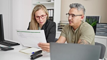 Wall Mural - Man and woman business workers using laptop reading document at the office