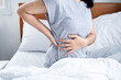 woman suffering from lower back pain , bad posture when sleeping in bed