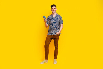 Sticker - Full size photo of pleasant smart guy wear stylish shirt trousers hold smartphone read notification isolated on yellow color background