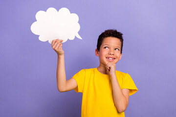 Wall Mural - Photo of minded clever boy wear trendy clothes hand hold white paper card look up empty space isolated on purple color background