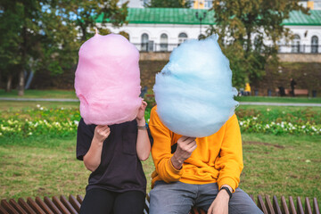 Two children are sitting with a large cotton candy blue and light blue. brother and sister, walk, childhood, sweets. without face