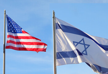 two large Israeli and American flags waving in the blue sky