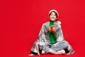 Sticker - Full body minded young woman wrapped in plaid wear Santa hat posing sit drink coffee milk look aside on area isolated on plain red background Happy New Year 2024 celebration Christmas holiday concept