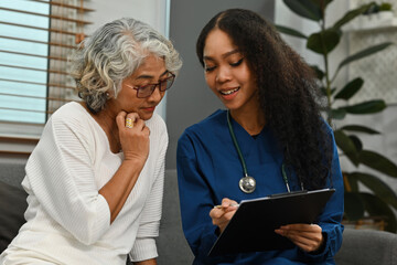 African-Asian nurse or caregiver explains the results of the health examination to the elderly woman at home. Health assessment of elderly patients in nursing homes