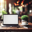 On the wooden table, you'll find a laptop with a white screen and a cup of coffee, set against a blurred background featuring a vibrant potted plant