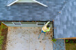 © ungvar - An employee is cleaning clogged roof gutter drain with dirt, debris, fallen leaves