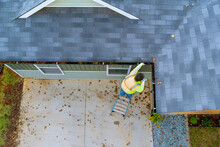 An Employee Is Cleaning Clogged Roof Gutter Drain With Dirt, Debris, Fallen Leaves