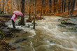 © Andrew Kornylak - A young girl in a pink jacket and umbrella leans over a flooding creek in the rain