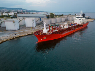 Wall Mural - Tanker ship refueling at an oil terminal with storage silo's in