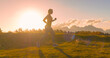 © helivideo - CLOSE UP, LENS FLARE: Athletic woman in sportswear runs on top of a grassy ridge