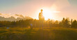 CLOSE UP, LENS FLARE: Sporty woman with a dog admires sunset at the grassy peak