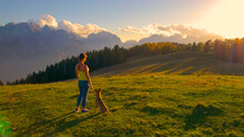 AERIAL: Attractive Woman Admires View Of The Mountains On A Hilltop With Her Dog