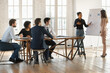 © fizkes - Confident young multiethnic speaker woman presenting sales report to diverse team. Indian manager explaining marketing data on flip chart to colleagues on meeting in boardroom modern space