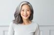 Stylish confident adult 50 years old asian woman  looking at camera on light background.  Middle-aged  women with silver gray short hair.  Beauty, skin care, spa concept. Plastic surgery