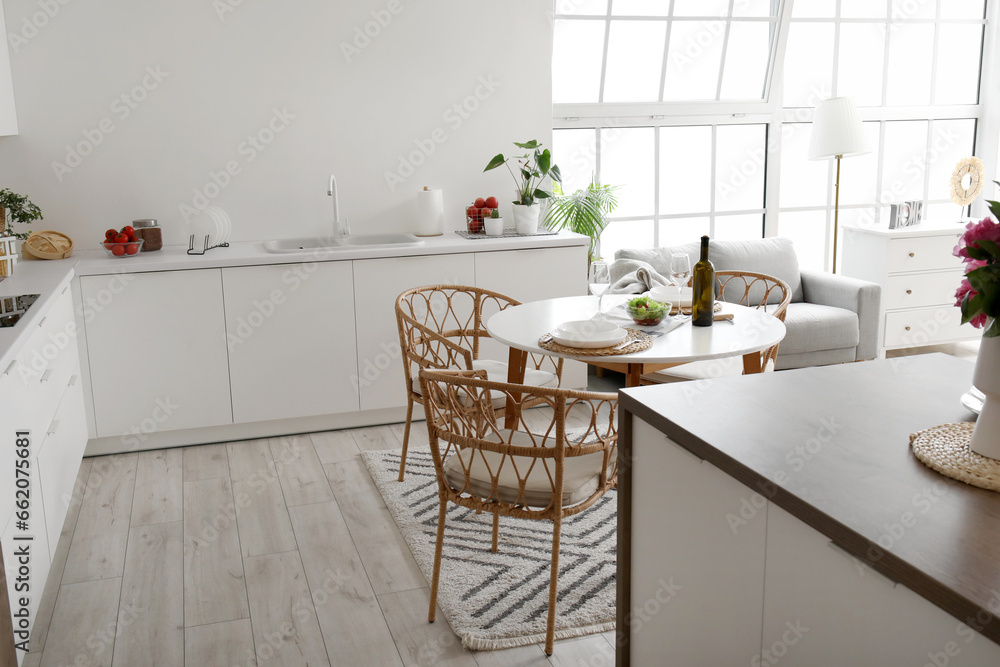 Interior of light open plan kitchen with served dining table