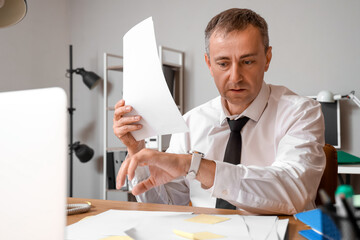 Wall Mural - Stressed mature businessman working under deadline in office