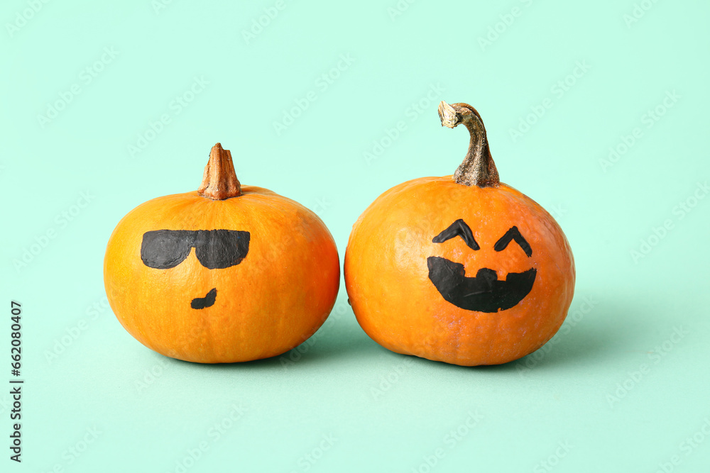 Funny Halloween pumpkins with drawn faces on turquoise background