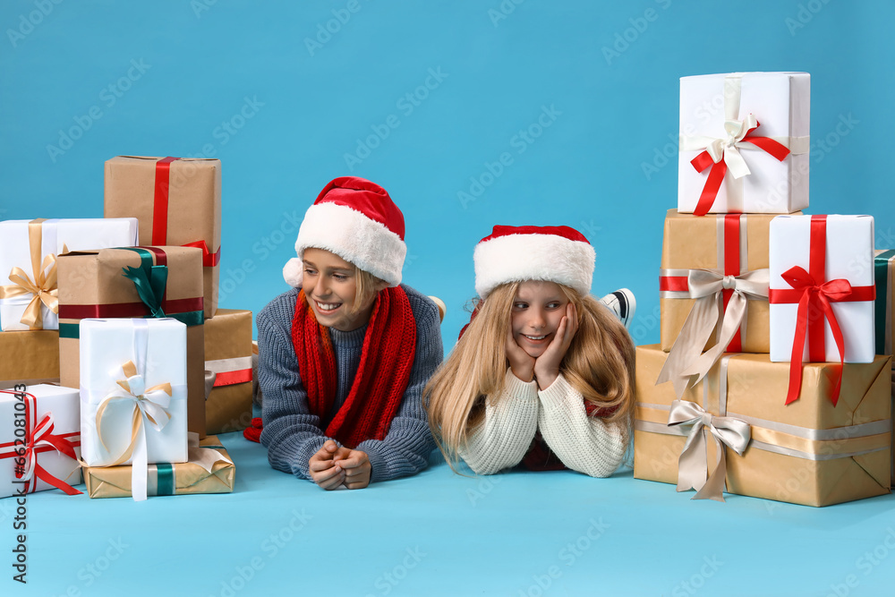 Little children with Christmas presents lying on blue background