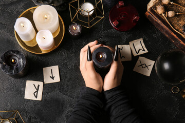 Wall Mural - Witch with burning candles and runes on dark background