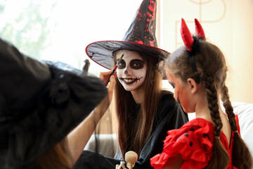 Poster - Mother painting face of her little daughter for Halloween at home