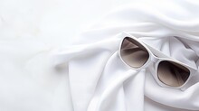 A Pair Of White Sunglasses On A White Fabric Background, Creating A Minimalist And Elegant Image. The Sunglasses Have A Cat-eye Shape And Dark Lenses, Reflecting Style And Sophistication.
