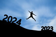 Concept Happy new year 2024 Silhouette of happy man jump from 2023 to 2024 on beautiful sky background.