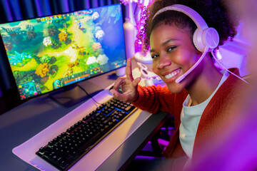 Host channel of gaming streamer, African girl playing fighting Moba game with joystick, wearing pastel headsets with mic, looking at the camera against background in neon color room. Tastemaker.