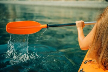 Kayak paddle sea vacation. Person paddles with orange paddle oar on kayak in sea. Leisure active lifestyle recreation activity rest tourism travel