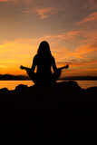 Fototapeta  - sylwetka kobiety medytującej na plaży przy zachodzie słońca