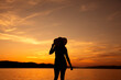 kobieta w kapeluszu na tle zachodzącego słońca nad morzem