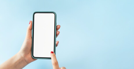 Female hands holding smartphone with mockup of blank screen on blue background.