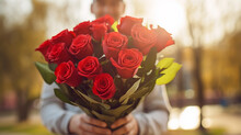 Man Holding Large Bouquet Of Charming Red Roses In Daylight Against An Outdoor Street Background Exudes Heartfelt Gesture Of Love And Romance, Adorable Gift For Woman You Love, Close Up Copy Space