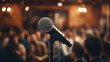 Microphone stands sharp against a blurred backdrop of a conference hall filled with attendees