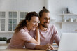 Excited cheerful young family couple getting great good news, income, using laptop, feeling joy, laughing in surprise, amazement, reading email letter, online note, winning prize