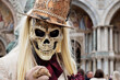 Person dressed up for Carnival of Venice wearing skull mask and white suit