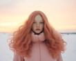 © Glittering Humanity - A stunning winter doll, with flowing pink coat and long hair, stands in a snowy landscape, gazing at the sky with a fierce beauty that captures the essence of fashion and femininity