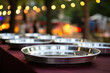 The close up detail of silver metallic trays or dishes lined up neatly on an outdoor wooden table for a garden party, blurry background. Generative AI.