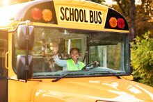 Portrait Of Joyful Young Black Female Driver Steering Yellow School Bus